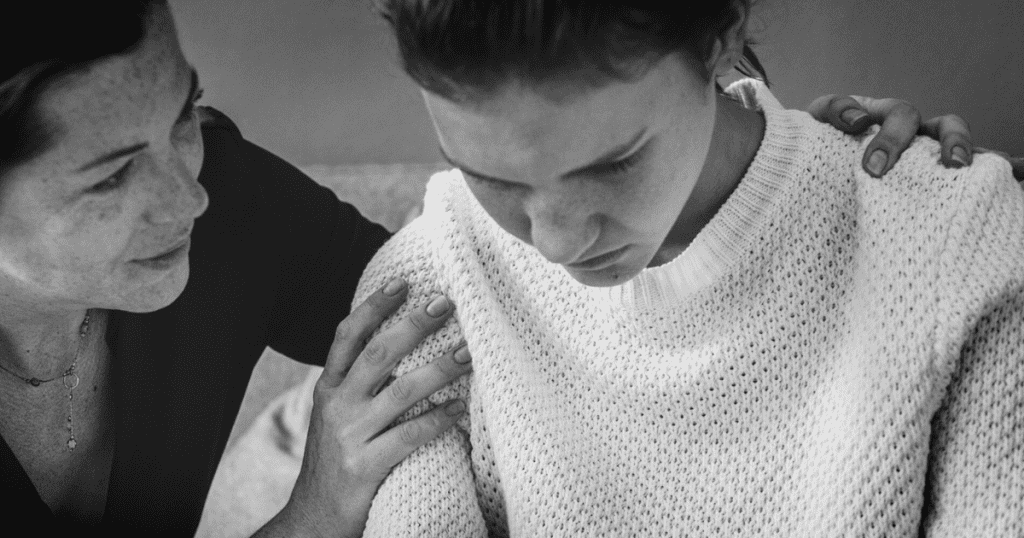 A black-and-white photo shows a woman manipulating another who looks down sadly, reflecting the control and emotional pressure narcissists impose through unspoken rules.