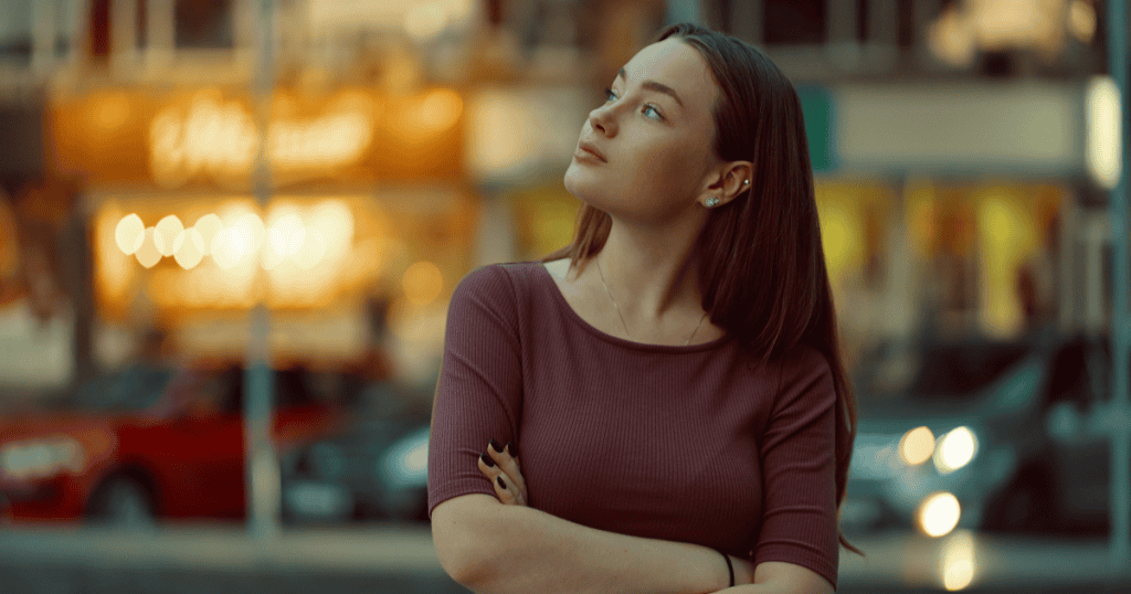 A woman standing with arms crossed and a steady expression, embodying the calm authority that disarms narcissists more effectively than heated confrontation.