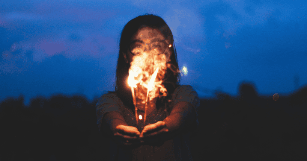 A woman holding sparklers at night symbolizes calling out a narcissist for playing the victim after causing chaos.