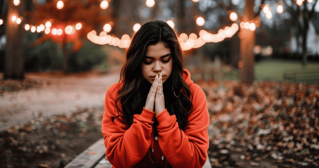 A woman sits with hands pressed together in reflection, symbolizing forgiveness done for self-healing, not for the narcissist.