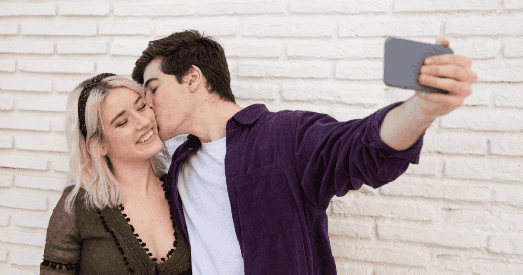 A man flaunts affection with a new partner for a selfie, echoing how narcissists parade someone new to provoke jealousy after a breakup.