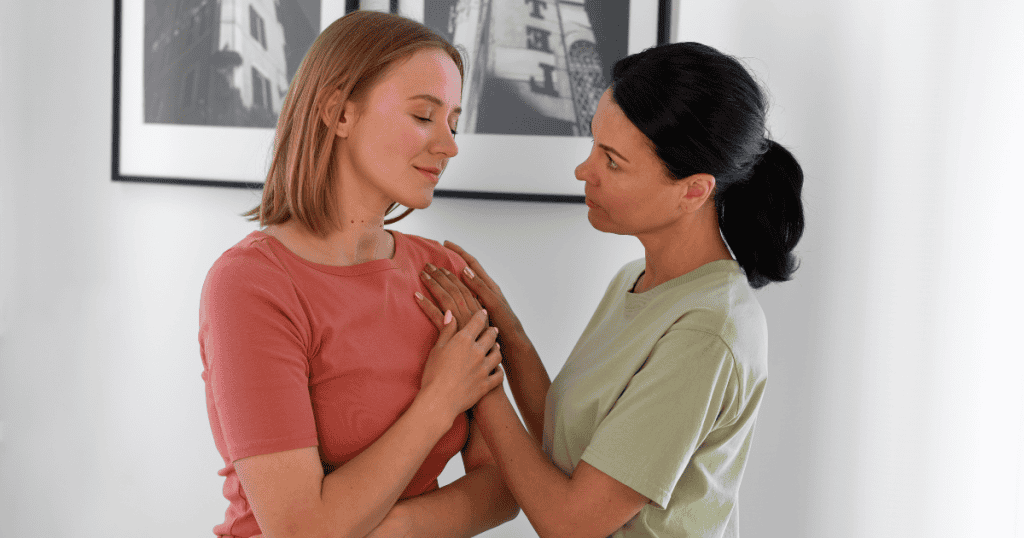 One woman places a hand on another's chest in a comforting gesture, attempting to project a depth of feeling that is the one thing she cannot fake.