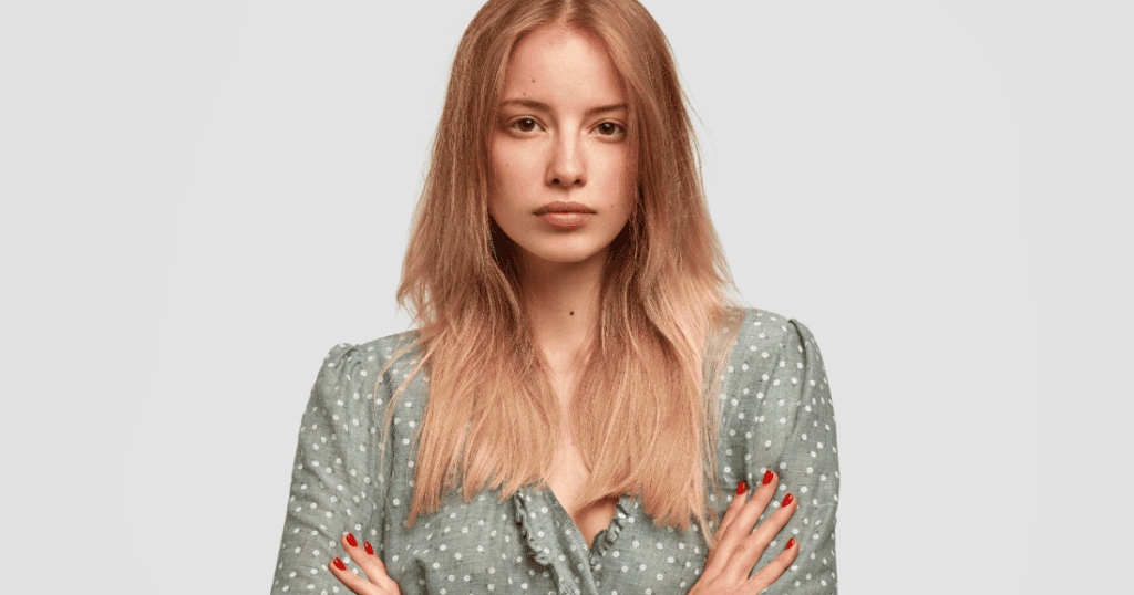 A woman stares forward with a completely neutral, stoic expression, embodying the total withdrawal of emotional reactions.