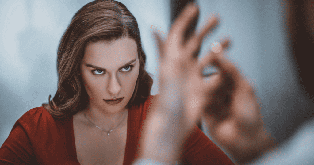 A woman in a red dress stares coldly at a blurred figure holding a ring, signaling the point where empathy is replaced by a calculated, icy detachment.