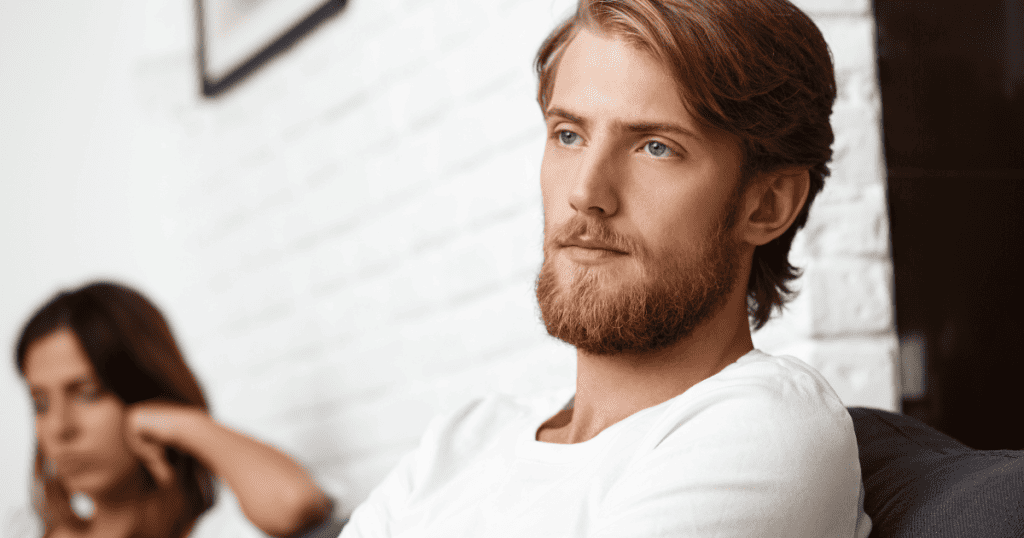 A man sits in the foreground with a distant, stoic gaze while a woman remains blurred and frustrated in the background, illustrating a predictable shift in emotional connection.