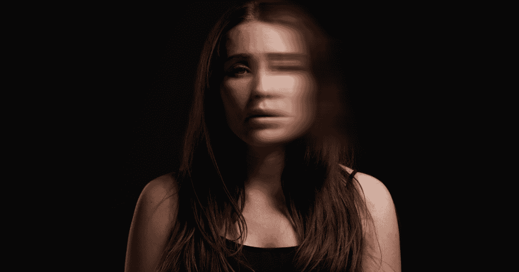 A woman’s face is partially blurred and trailing in a dark void, depicting the fragmented state of a self that had to change form to endure.