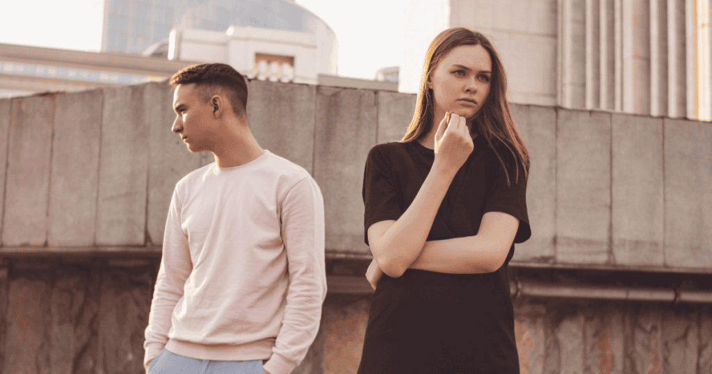 A man and woman stand back-to-back against a concrete ledge, emphasizing the newfound boundaries and distance required to protect one’s peace.