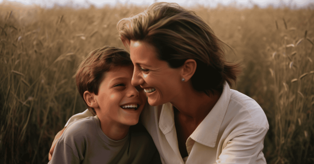 A woman laughs softly while embracing a young boy in a golden wheat field, capturing a moment where composure and kindness lead the way.