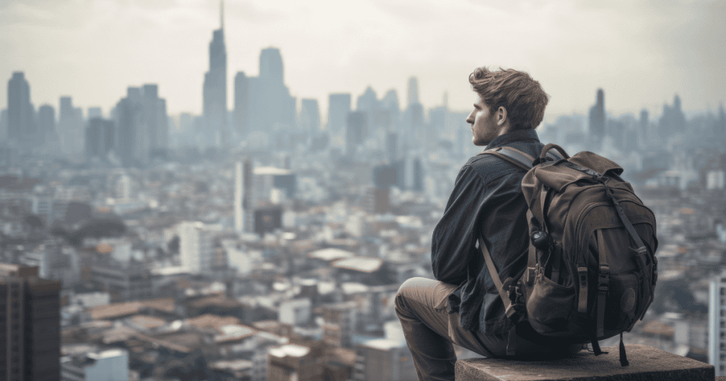 A man with a backpack sits on a high ledge looking out over a sprawling, hazy metropolis, finding a new perspective that only comes with significant physical separation.
