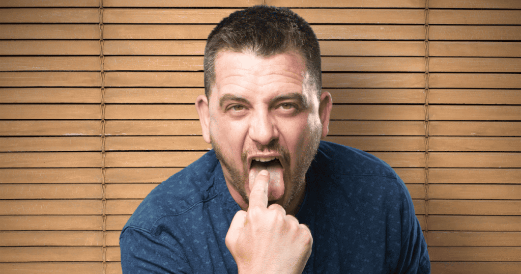 A man makes a mocking, aggressive face with his finger in his mouth, capturing the volatile reaction that often follows a direct verbal challenge.