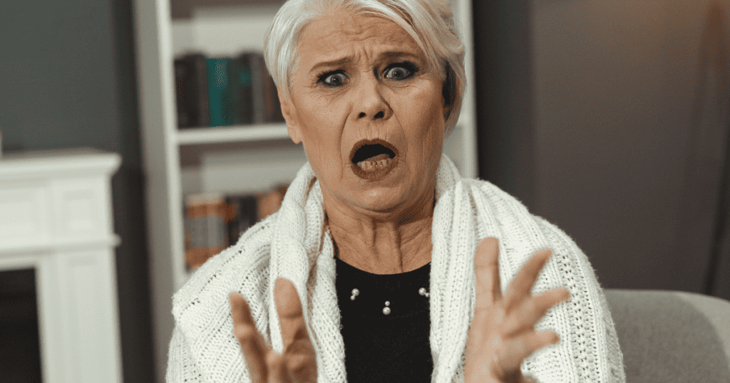 An older woman with an open mouth and raised hands looks on in total shock, illustrating the chaotic aftermath of a specific revelation.