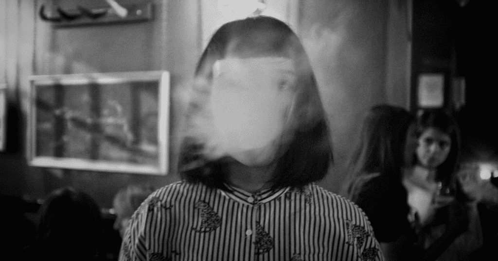 A blurred, obscured face of a woman in a crowded room represents the hollow and ghostly nature of a person who lacks a true emotional core.