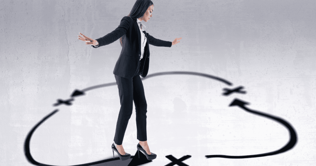A woman in a suit carefully balances on a dark, circular path drawn on the floor, representing the strategic maneuvers required to step out of a repetitive emotional trap.