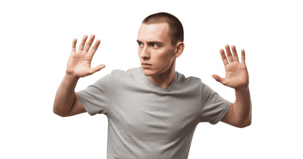 A man looks over his shoulder with his hands raised defensively, mirroring the reactive state of someone whose internal defenses have been triggered.