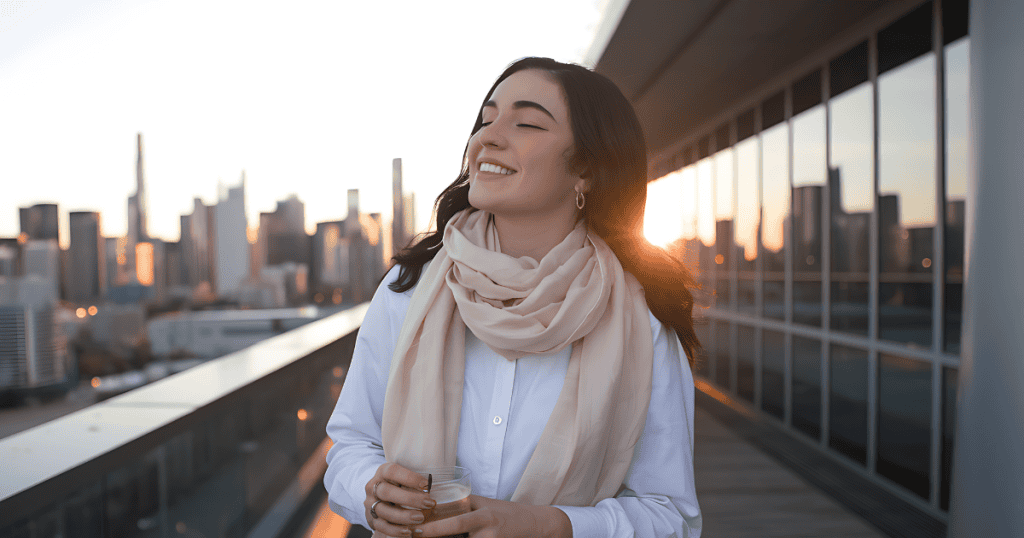 A woman stands on a high balcony with her eyes closed and a peaceful expression, finding a moment of internal stillness amidst a sprawling, complex environment.