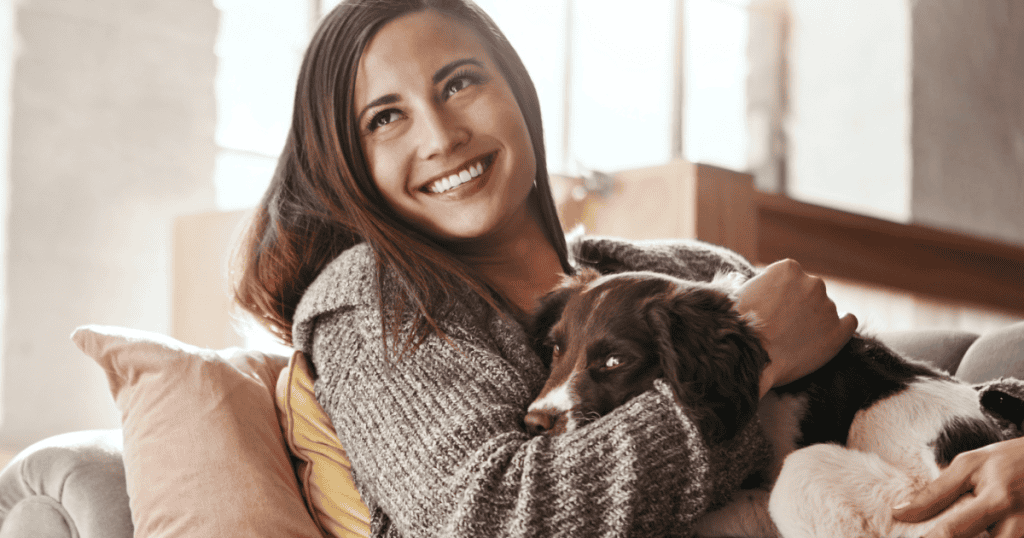 A woman smiles warmly while embracing her dog, showing a moment of genuine connection that often goes overlooked.