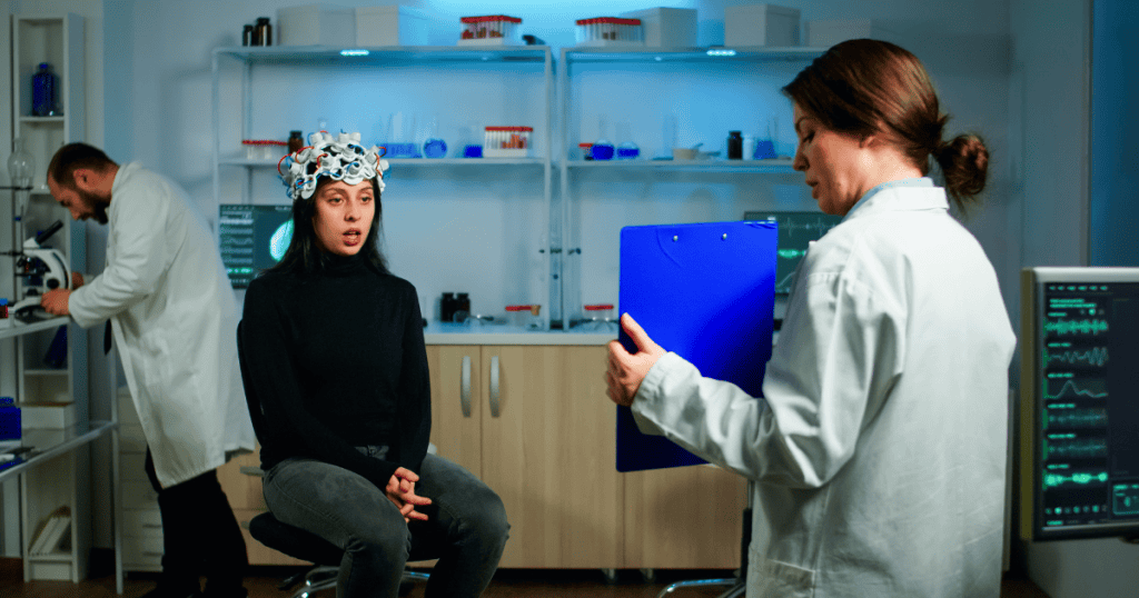A researcher monitors a woman wearing a brain-scanning headset, seeking to map the internal mechanics behind outward behavior.