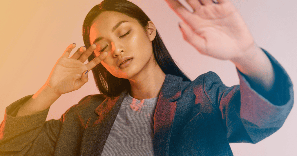 A woman shields her eyes from a bright, multi-colored light with her hand, signaling the sudden withdrawal of a primary source of light and attention.
