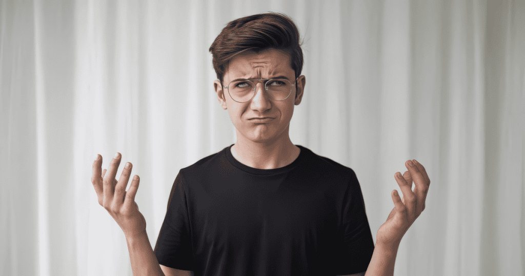 A young man looks upward with a confused and helpless facial expression, opting for a posture of harmless bewilderment rather than direct challenge.