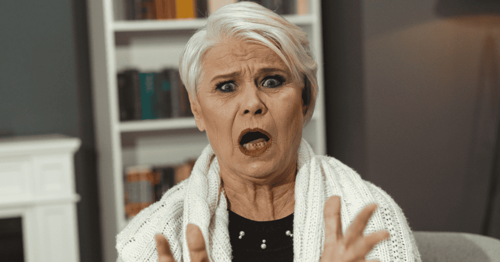 A woman with short white hair looks toward the camera with a shocked, wide-mouthed expression, capturing the visceral panic of a sudden loss of influence.