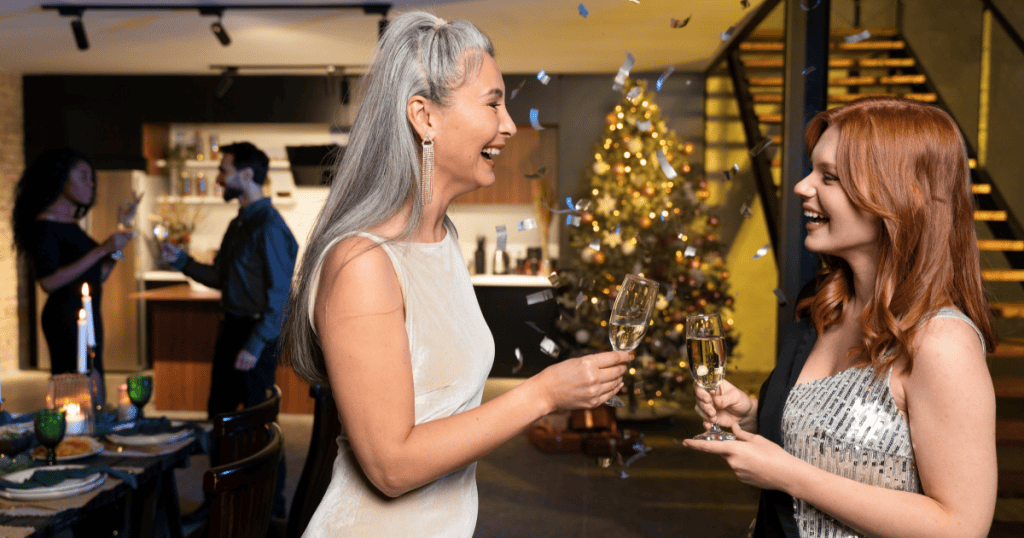 Two women smile and socialize at a holiday gathering, reflecting the importance of setting emotional boundaries before entering triggering family environments.