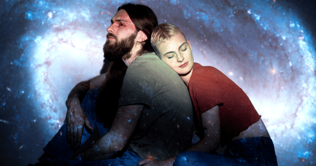 A couple leans against each other beneath a cosmic backdrop, symbolizing the intense emotional pull between empaths and narcissists.