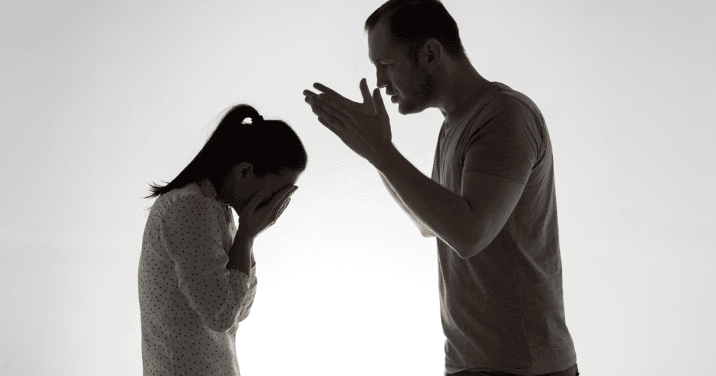 A man looms over a weeping woman in a high-contrast room, highlighting the harsh reality of maintaining a script over a soul.
