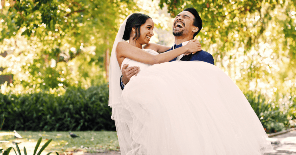 A man joyfully lifts a laughing woman in her wedding dress, embodying the genuine hope often brought to a hollow stage.