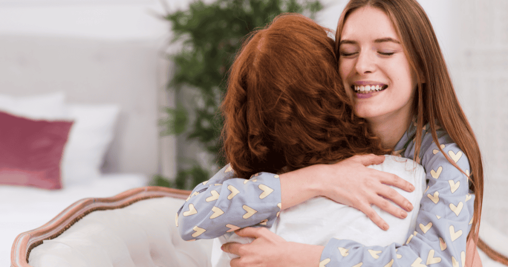 Two women embracing warmly at home, reflecting how an adult raised by a narcissist often mistakes constant caretaking and self-sacrifice for love.