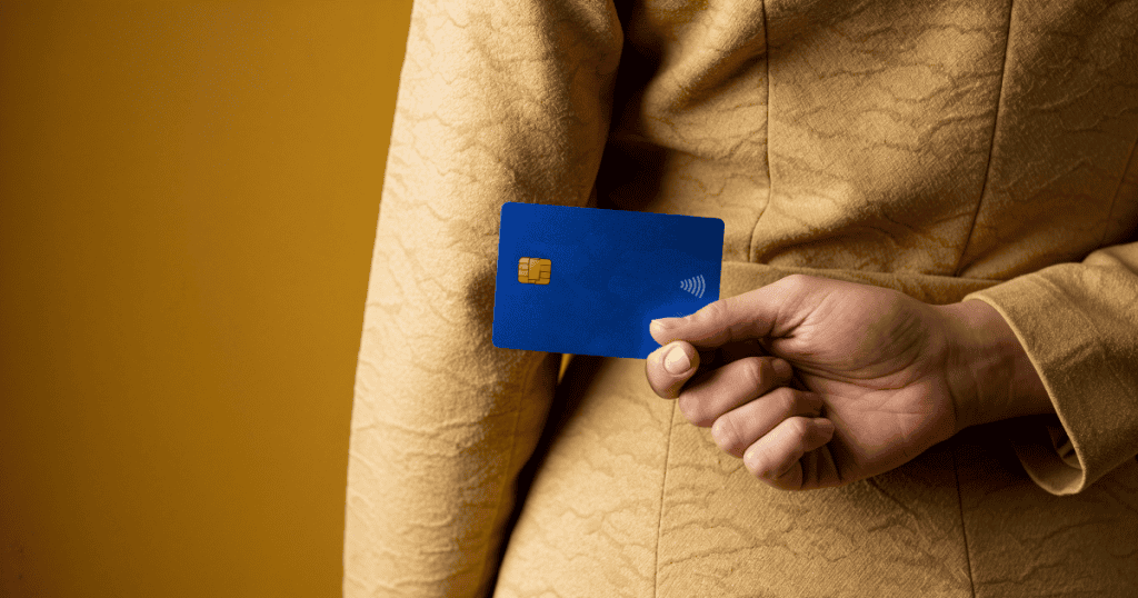 A hand discreetly slipping a credit card behind their back, representing how a narcissist quietly conceals or removes shared cards just before vanishing with the money.