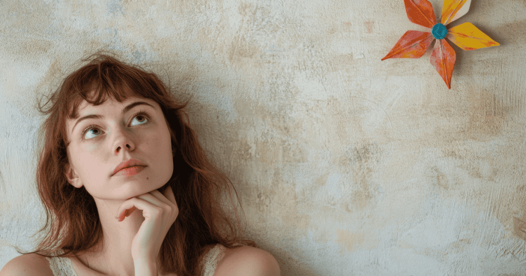 A young woman rests her hand on her chin and looks upward thoughtfully against a textured wall, reflecting on behaviors that appear perfectly ordinary to anyone else.