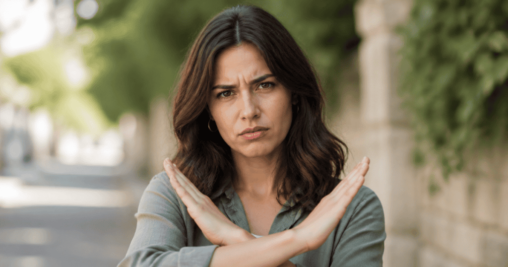 A determined woman looks directly at the camera while making a firm "stop" gesture with her arms crossed in an 'X', powerfully representing the firm boundaries and what to watch for before these tricks even begin.