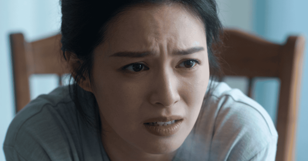 A close-up portrait captures a woman with a deeply furrowed brow and a pained, distressed facial expression, visually embodying the profound physiological and psychological toll of a deeply rooted trauma response.