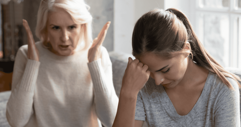 An older woman raging while a younger woman sits in defeated silence, showing why a narcissist's ego will never allow them to lose an argument gracefully and save the relationship in the process.