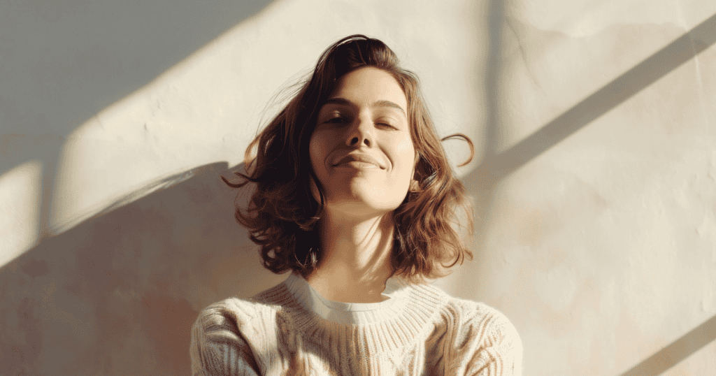 A woman tilts her head back with a serene, knowing smile in the warm sunlight, reflecting the quiet confidence of trusting your own instincts above superficial fixes.