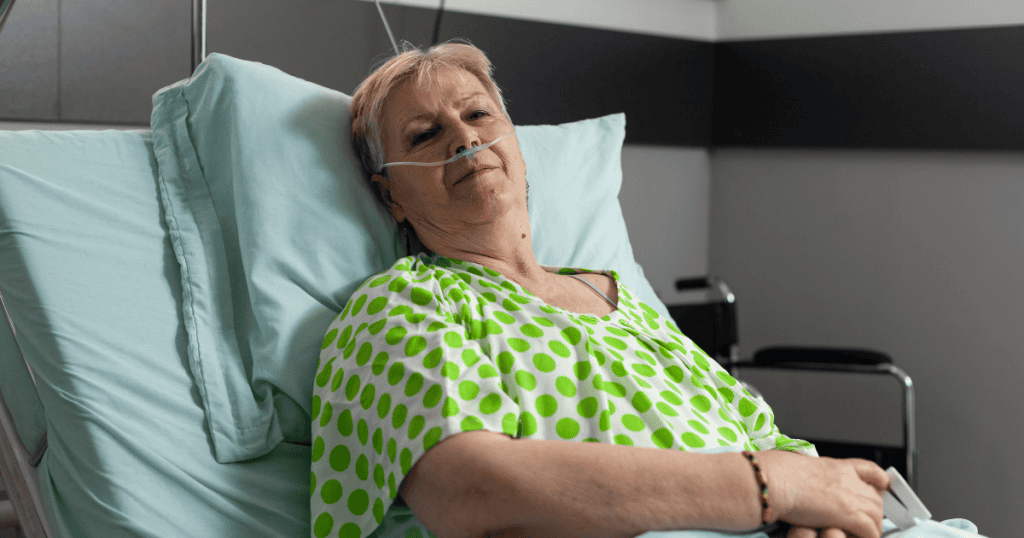An elderly patient wearing nasal oxygen cannula lies in a hospital bed looking forward, depicting how medical crises can become the ultimate bid to pull family back into orbit.