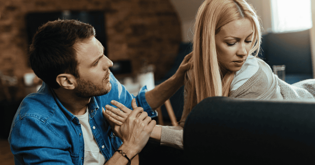 A distressed woman turns her face away on a sofa while a pleading man grips her hand, illustrating the heavy emotional toll when repeated excuses fail to mend broken trust.