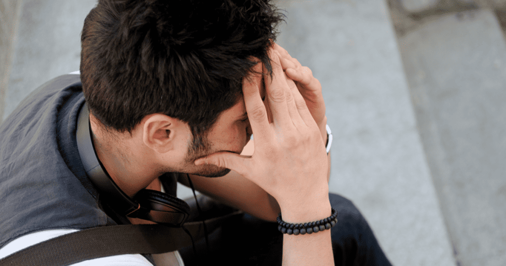 A young man sits alone on stone steps with his head in his hands, revealing the private hurt a narcissist experiences from wounds they could never bring themselves to acknowledge.