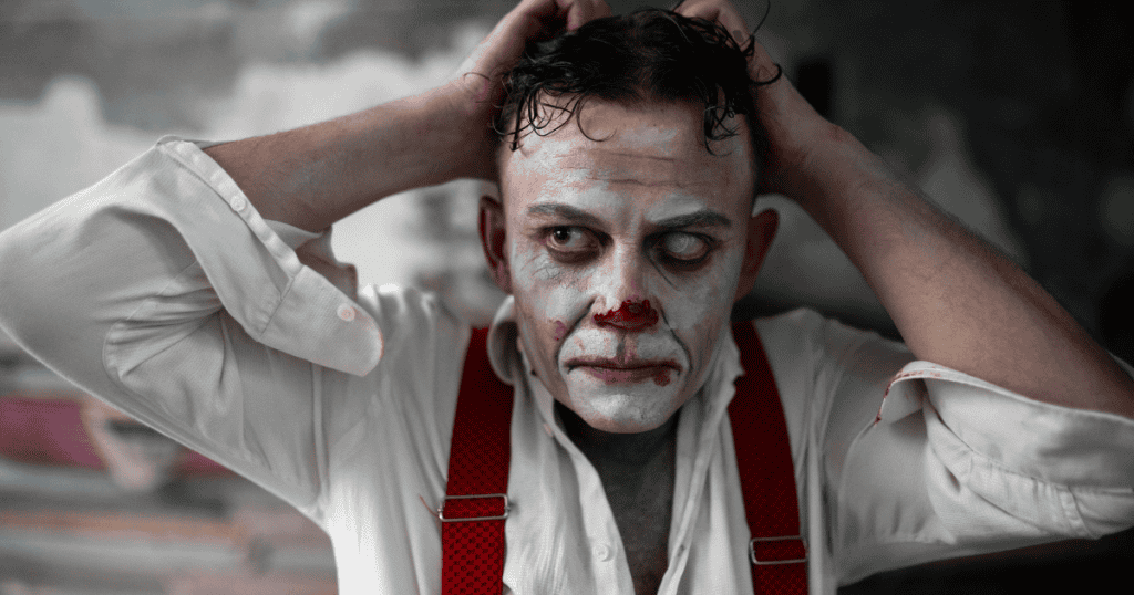 A man wearing disheveled clown makeup grips the back of his head with wide, unhinged eyes, illustrating the complete unraveling that happens when manipulative games fail to work.