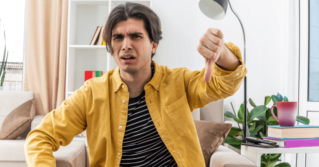 A man giving a firm thumbs down with a contemptuous scowl, depicting the reflexive dismissal a narcissist uses to invalidate their partner's feelings and make them doubt their own emotional reality.