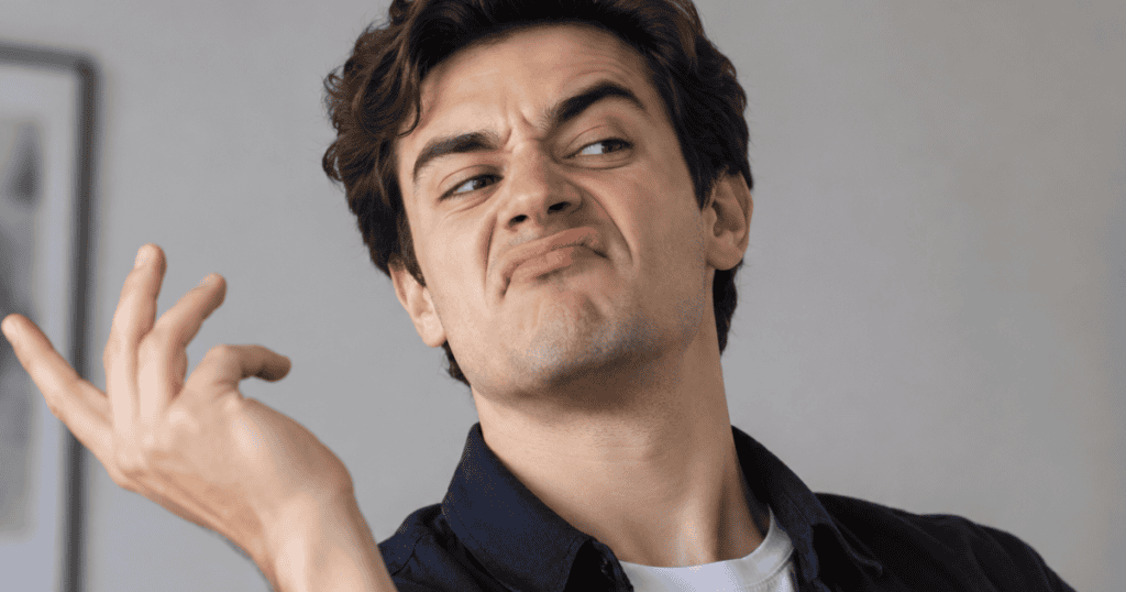 A man tilts his head with an exaggerated, contemptuous smirk while flicking his hand dismissively, depicting the overt sneer of superiority meant to diminish another person's voice.