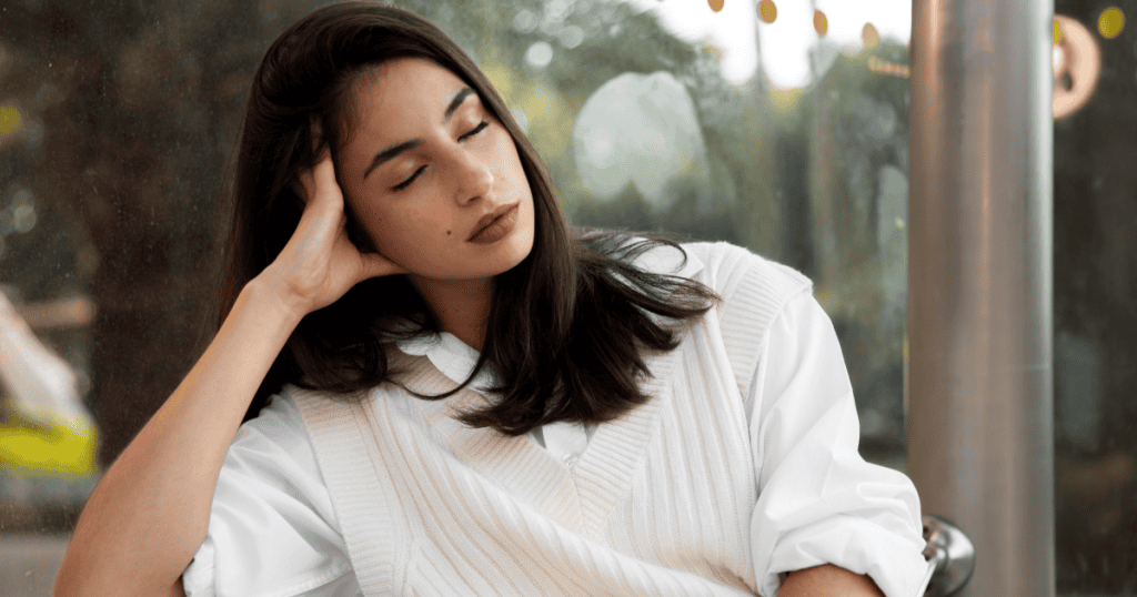 A woman rests her head against her hand with eyes closed, looking drained and weary, reflecting how conscientiousness can be exploited until it becomes exhausting.