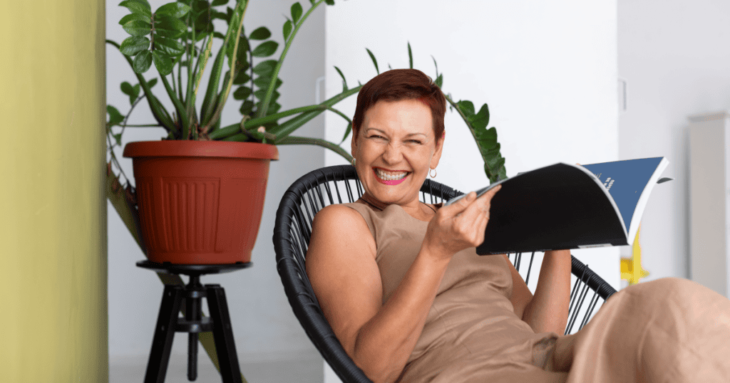 A woman laughs brightly while relaxing in a chair with a magazine, her carefree amusement underscoring the lack of genuine substance behind the narcissist's polished exterior.