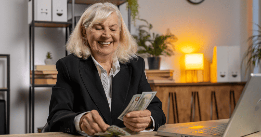 A woman gleefully counting cash at her desk, depicting how a narcissist will quietly redirect money or resources to sabotage milestones that should belong to you.