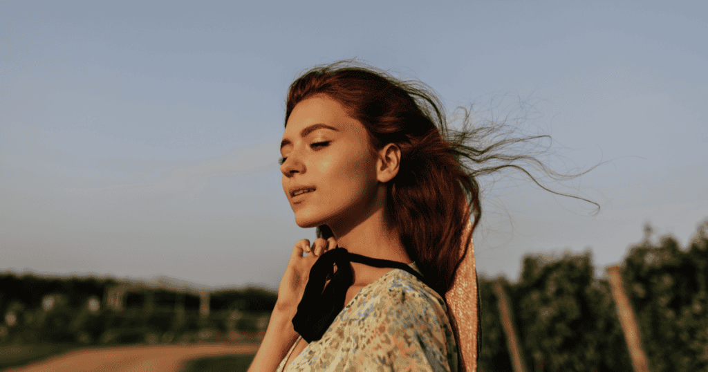A woman with windswept hair basks peacefully in golden sunlight, her serene expression reflecting the freedom of releasing a burden that was never hers to carry.