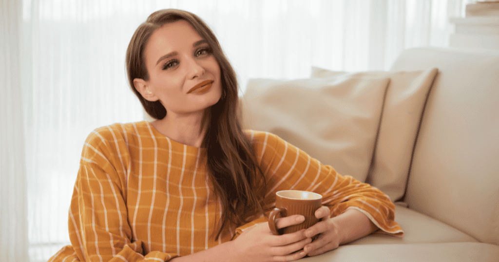 A woman relaxes on a sofa holding a warm mug with a soft, self-assured smile, suggesting that true peace comes from focusing on your own healing rather than just understanding the narcissist who hurt you.