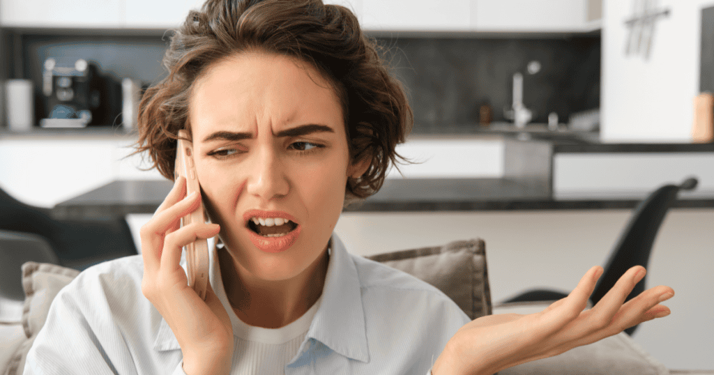 A frustrated woman frowns and gestures in disbelief while on the phone, capturing the confusion of realizing a narcissist treats money with careful respect but feels free to mistreat you.