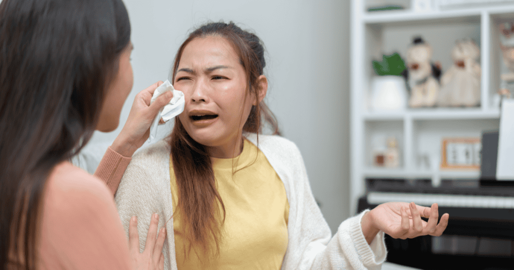A woman cries dramatically while another comforts her, wiping her tears, capturing performed remorse that masks a lack of genuine accountability.