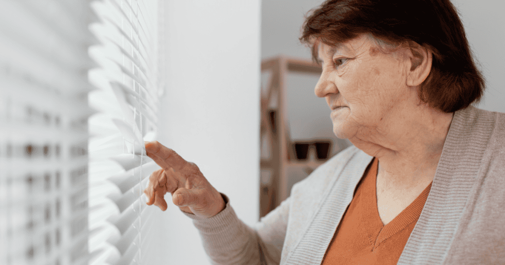 A woman peers watchfully through window blinds, embodying the anxious need for control that can unravel if they lose their grip on someone.