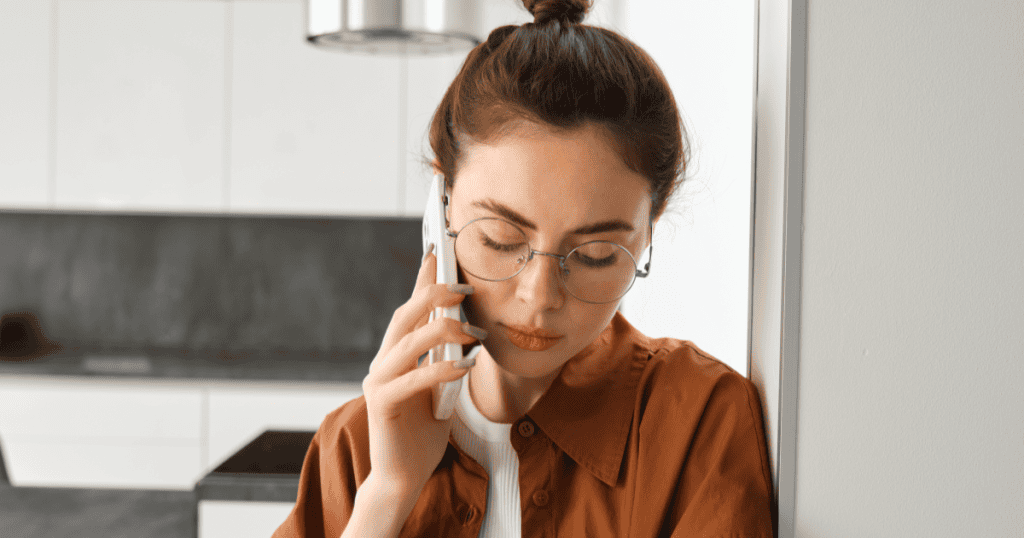 A woman in glasses closes her eyes while talking on the phone, her weary composure reflecting the clarity that comes once the pattern finally makes sense.